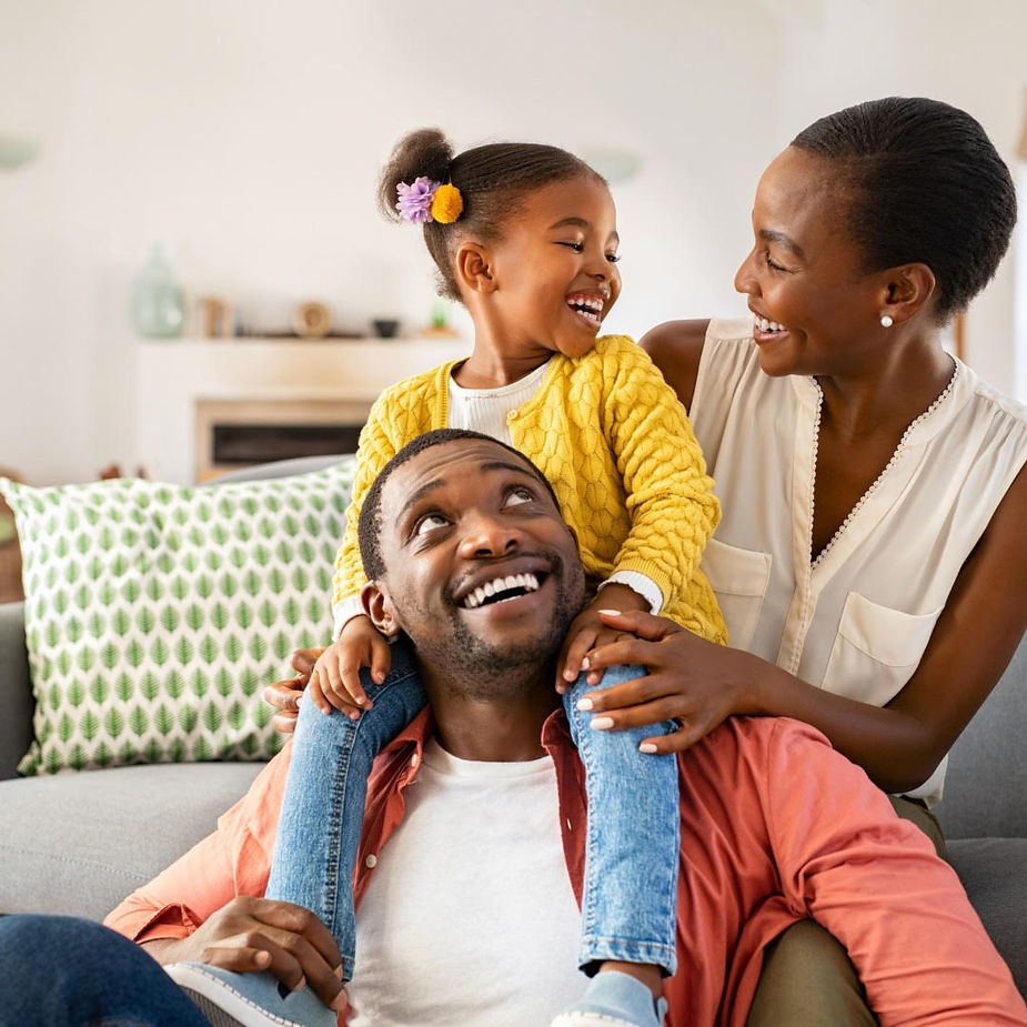 A happy black family comprising of a father, mother, and child- interacting happily together