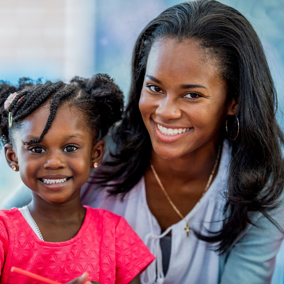 Smiling woman and young girl in posing together and both appear happy and joyful.