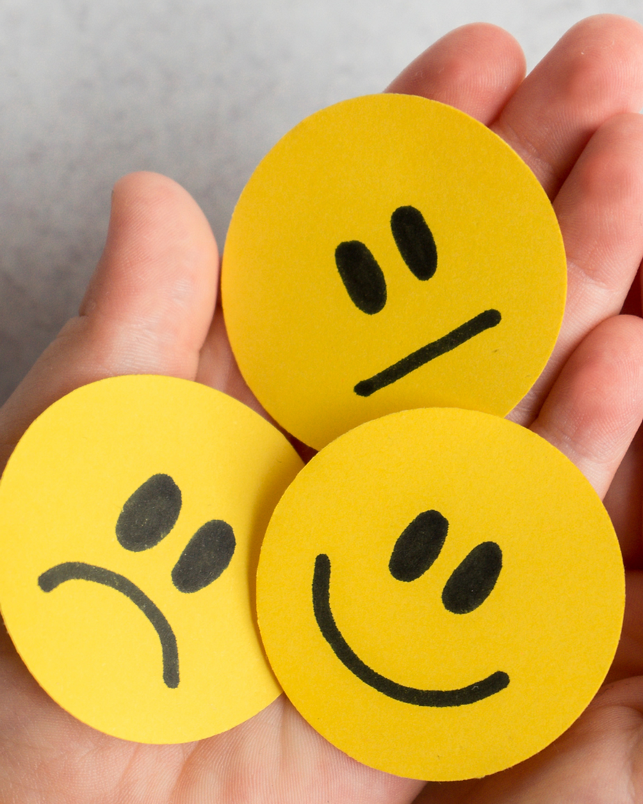 Hand holds three yellow visual cards of emotions display