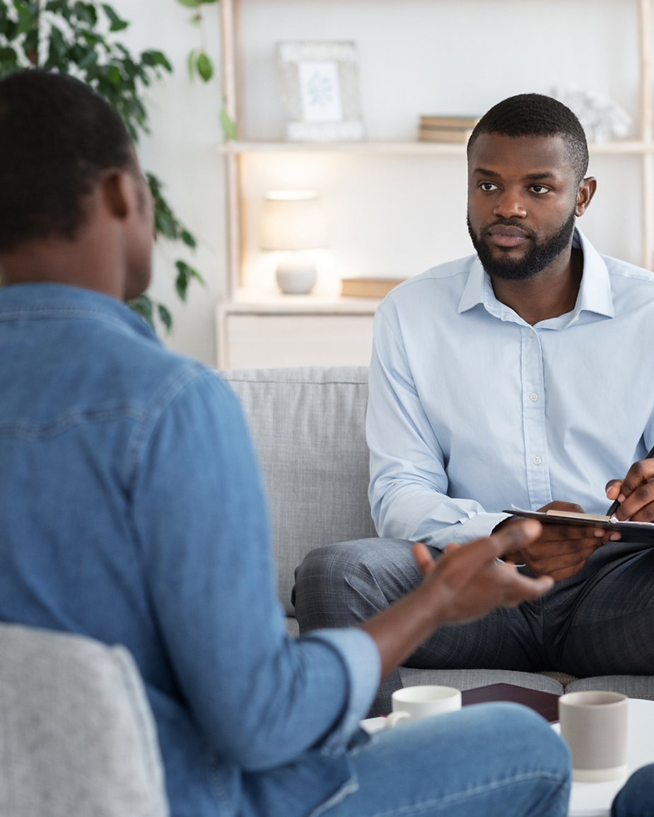 A therapist and parent sitting on a couch engaged in tracking a child's progress.
